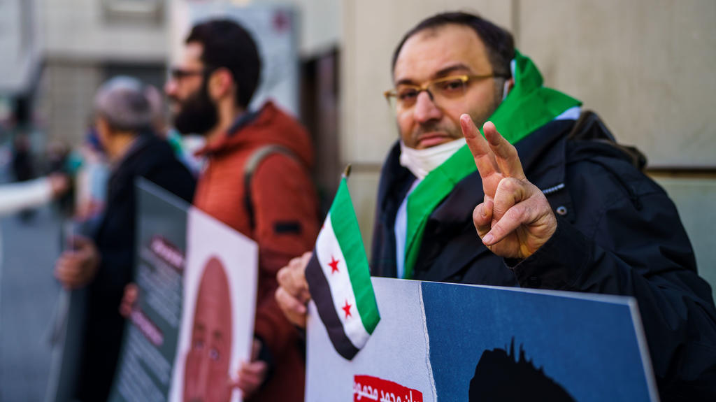 Ein syrischer Aktivist macht vor dem Gerichtsgebäude das ·Victory-Zeichen·. Vor dem Oberlandesgericht beginnt am Mittwoch ein weiterer Prozess wegen Verbrechen gegen die Menschlichkeit im Bürgerkriegsland Syrien. A