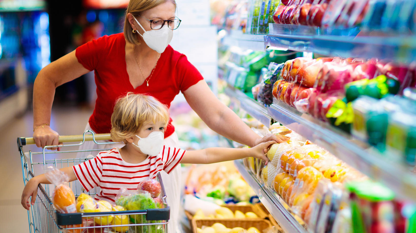 Shopping with kids during virus outbreak. Mother and child wearing surgical face mask buying fruit in supermarket. Mom and little boy buy fresh vegetable in grocery store. Family in shop.  (Shopping with kids during virus outbreak. Mother and child w