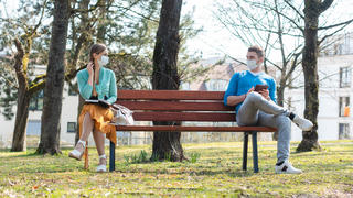 Ein Mann und eine Frau sitzen draußen auf einer Parkbank.