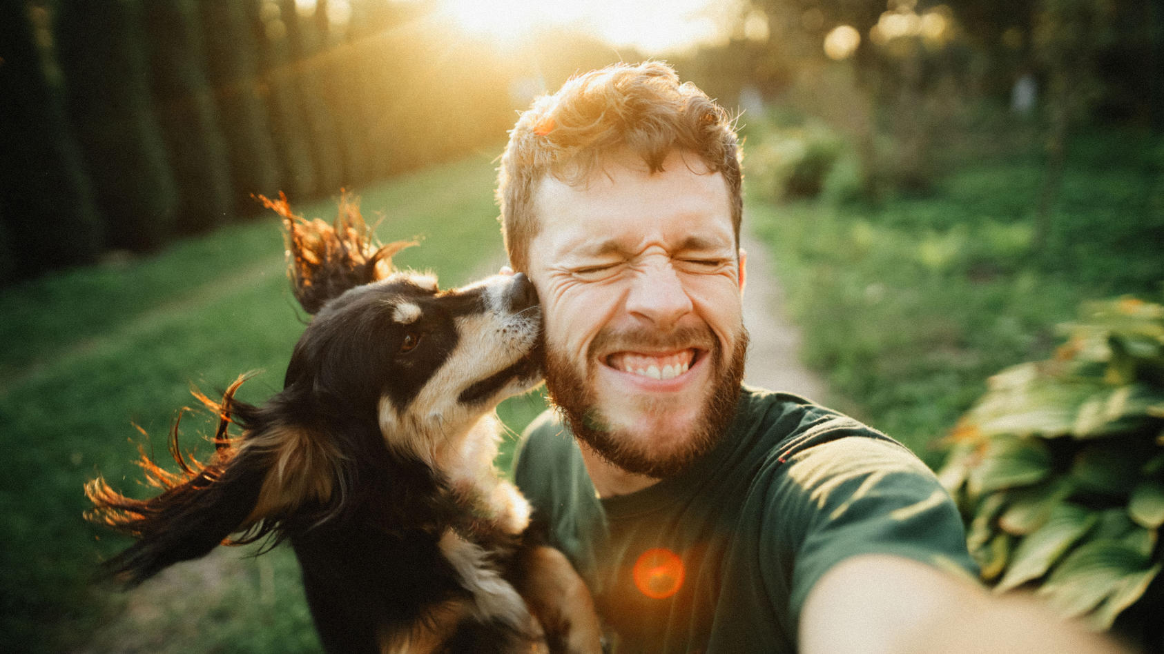 Mann mit Hund auf dem Arm macht ein Selfie.