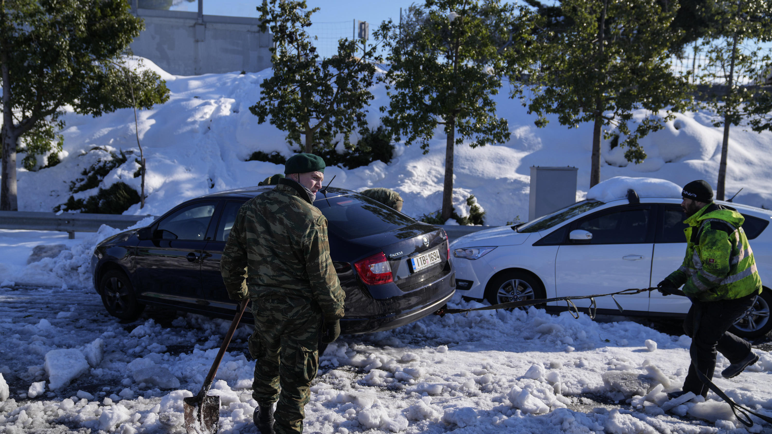 Griechenland, Athen: Zwei griechische Soldaten versuchen ein im Schnee festgefahrenes Auto auf der Autobahn Attiki Odos zu befreien. 