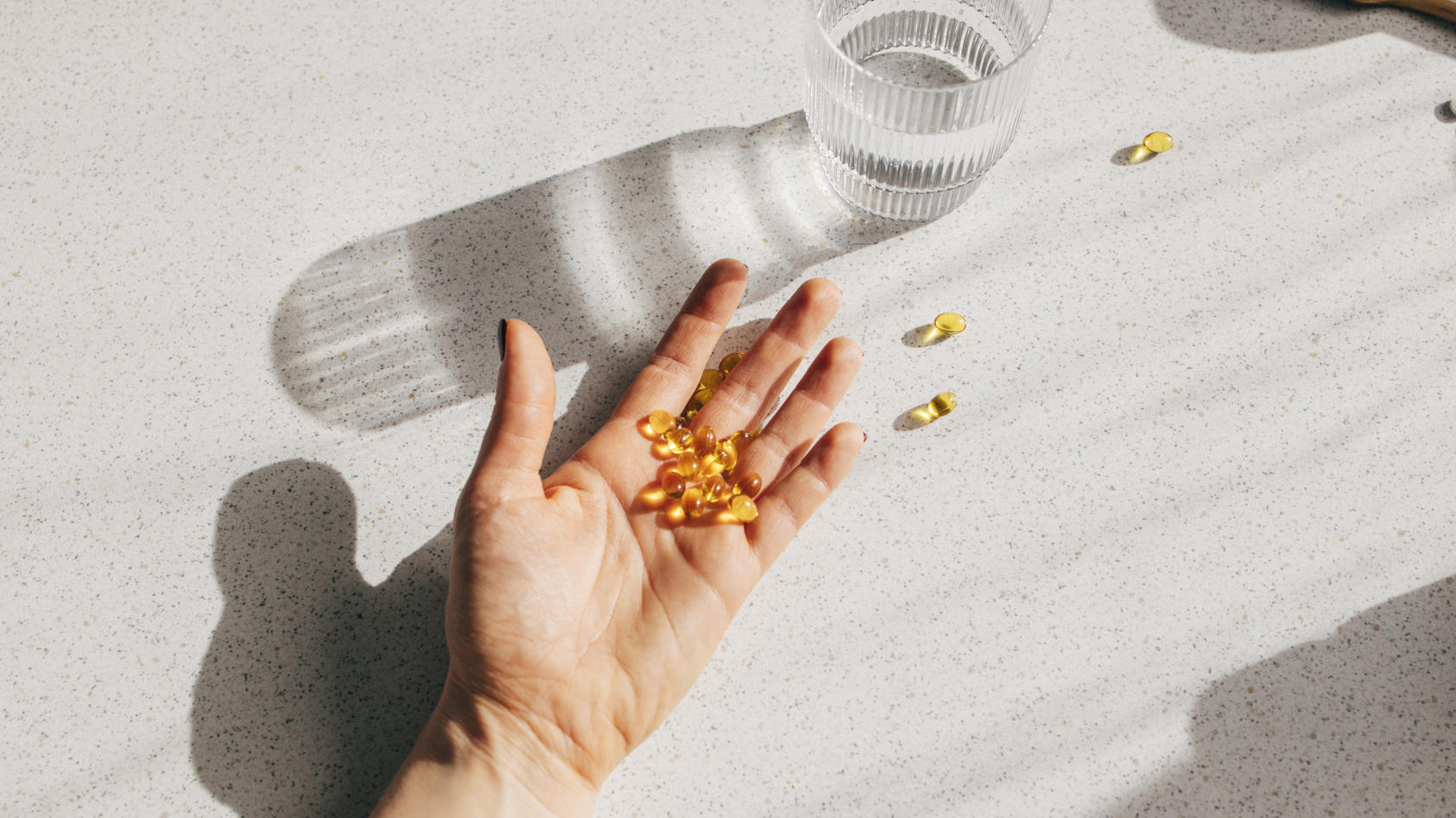 Eine Frau hält in ihrer Hand Vitamin-D-Kapseln, die sie einnimmt.
