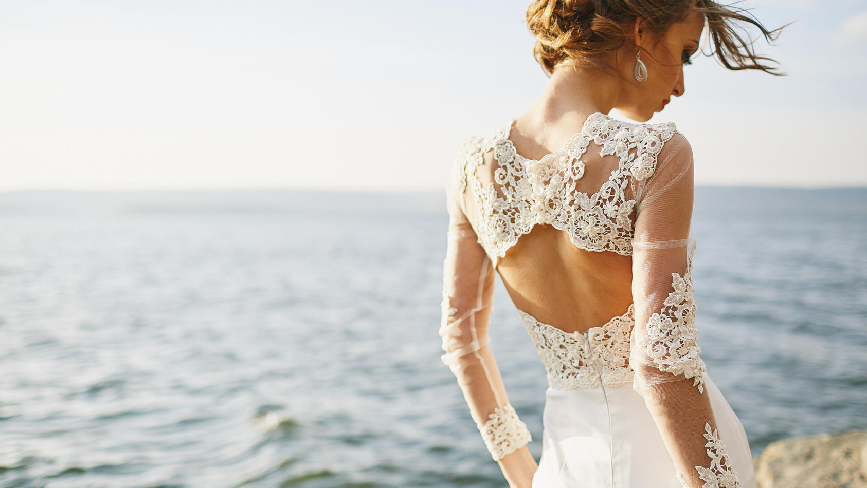 Frau in Hochzeitskleid am Strand.