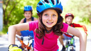 Portrait of a little girl riding her bike ahead of her friends