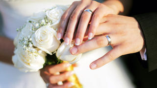 Wedding rings, bouqet and hands holding