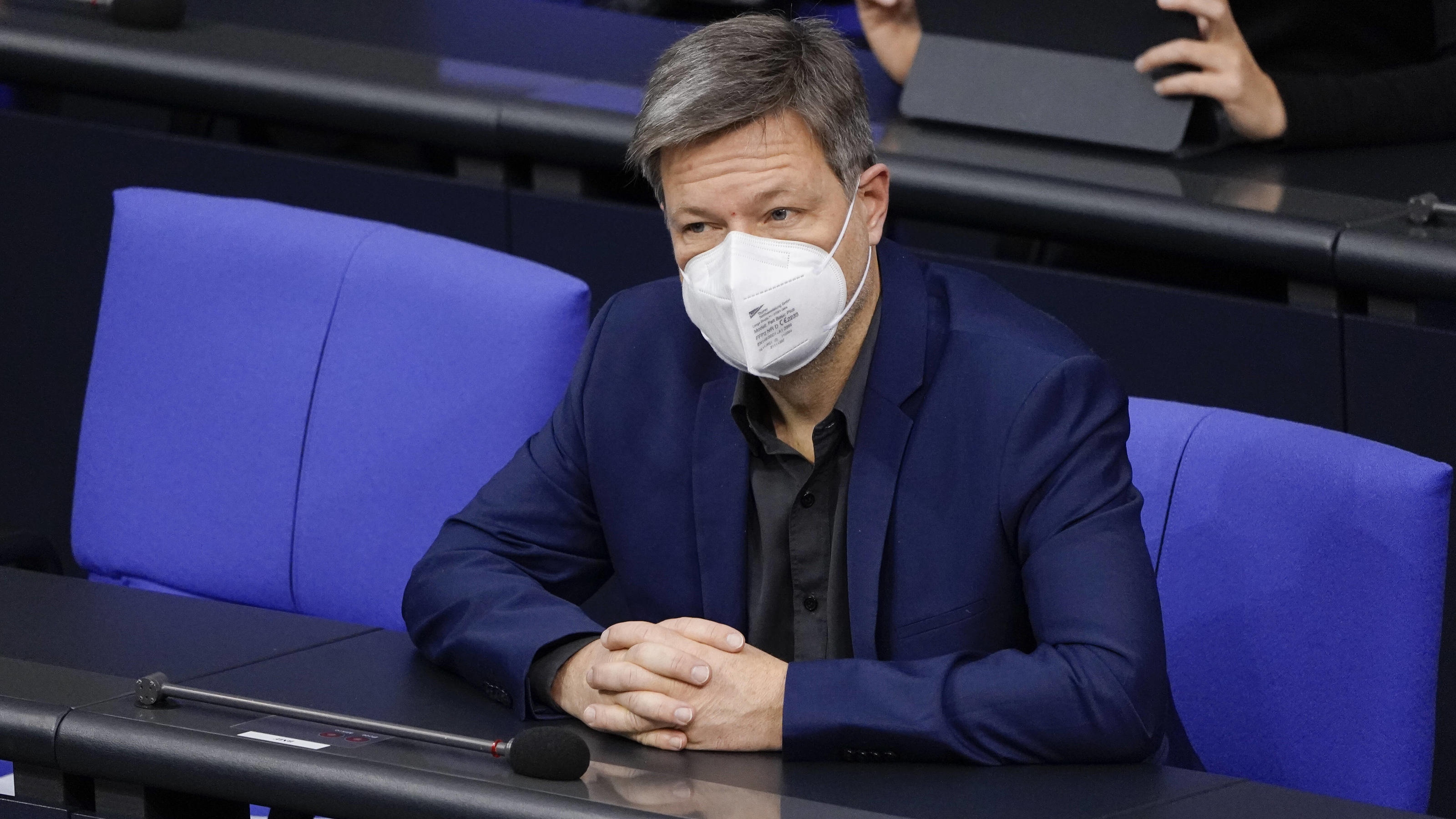 Wirtschafts- und Klimaminister Robert Habeck sitzt im Bundestag und trägt eine weiße FFP2-Maske. 