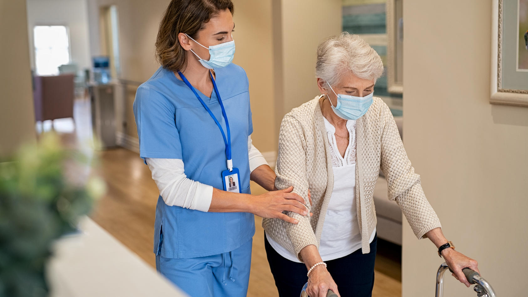 Eine Krankenschwester bzw. Altenpflegerin kümmert sich während der Corona-Pandemie um eine Seniorin.