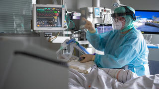 PRODUKTION - 16.02.2022, Hessen, Fulda: Eine Intensiv-Pflegerin versorgt einen schwer an Corona erkrankten Patienten auf der Intensivstation des Klinikums in Fulda. Viele Patienten mit schweren Verläufen liegen mehrere Wochen auf der Intensivstation, rund die Hälfte der künstlich beatmeten Patienten stirbt. (zu dpa "Sorgen um Engpässe in Kliniken und Altenheimen wegen Impfpflicht") Foto: Boris Roessler/dpa +++ dpa-Bildfunk +++