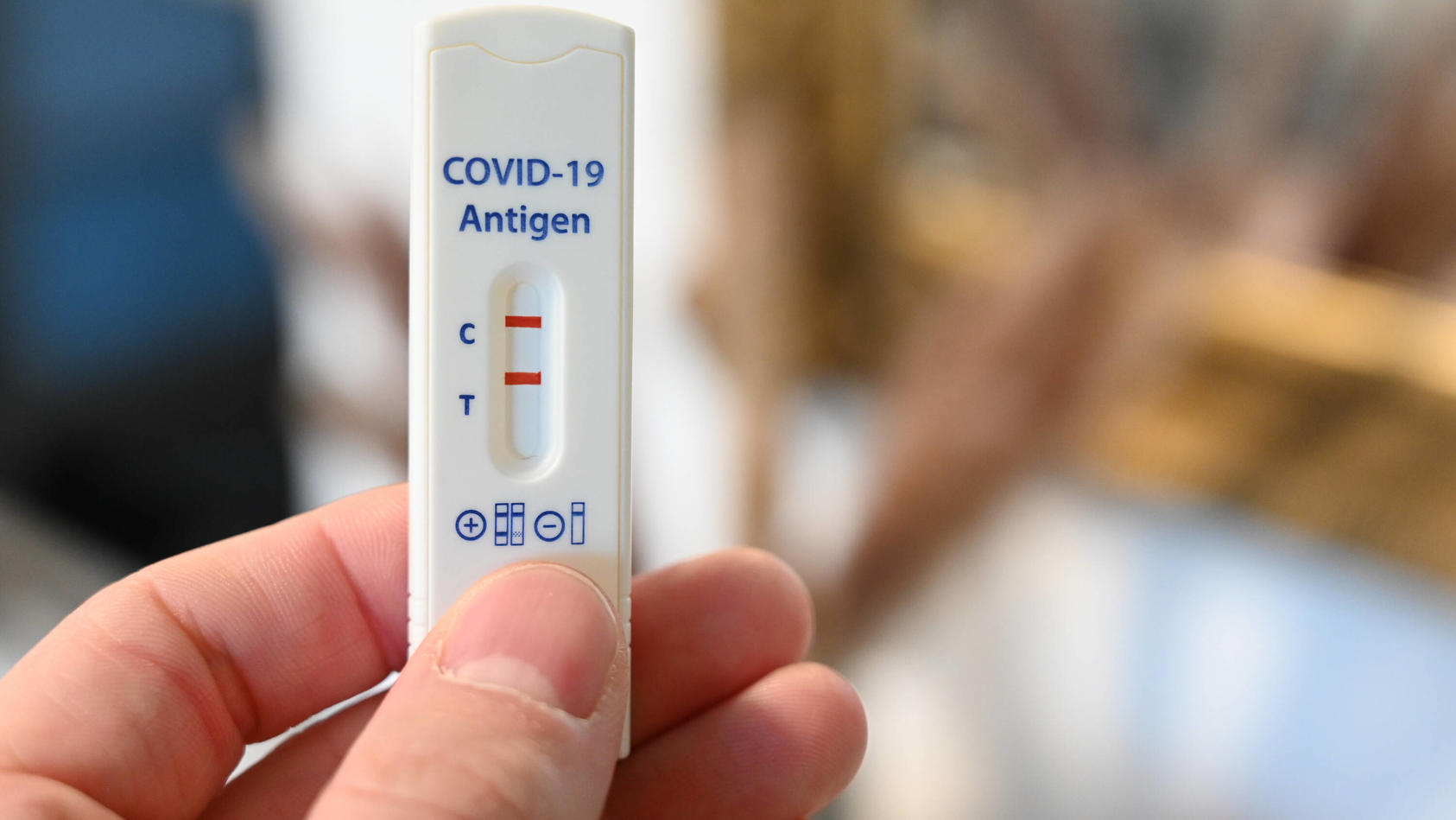 Person hält positiven Corona-Schnelltest in der Hand.