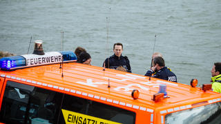 Rettungskräfte von Feuerwehr und Polizei stehen am Rhein in Köln (Nordrhein-Westfalen) am 15.03.2014. Ein sechsjähriges Mädchen ist an dieser Stelle im Fluss ertrunken. Ein Jogger, der hinterher sprang um das Kind zu retten, verschwand in der Strömung und blieb trotz zweistündiger Suche mit Rettungsbooten und Hubschraubern im Rhein verschwunden. Foto: Costa Belibasakis/dpa +++(c) dpa - Bildfunk+++