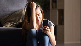Junge Frau schaut voller Sorge auf ihr Smartphone