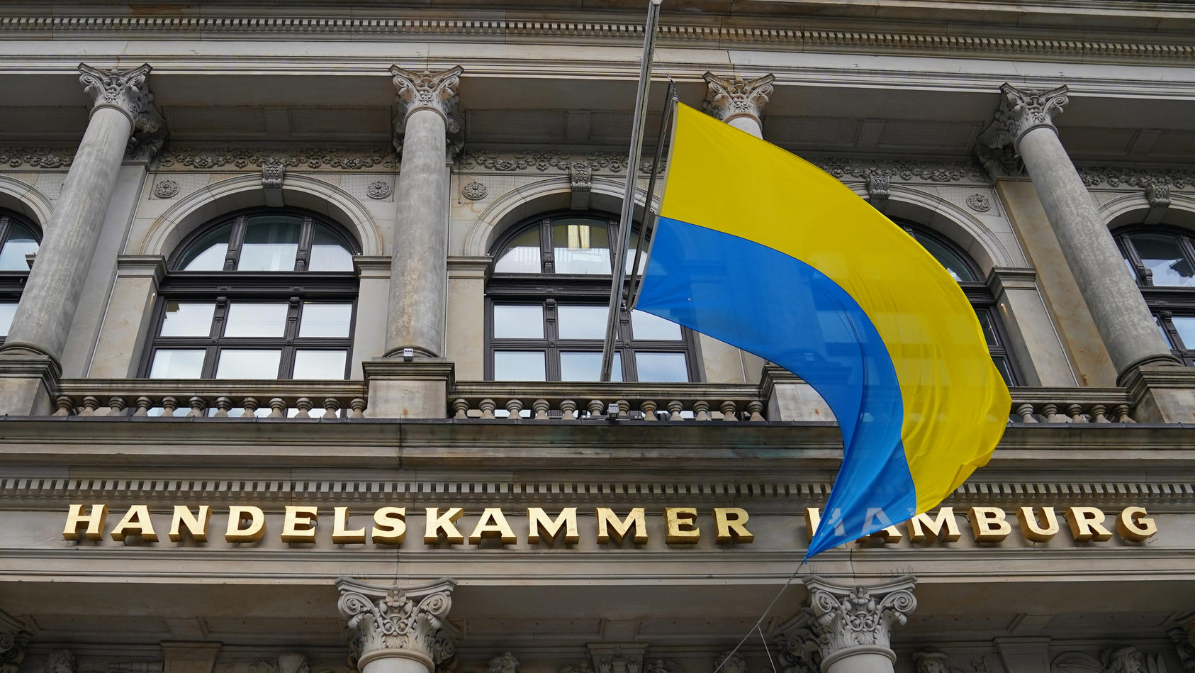 24.02.2022, Hamburg: Die Flagge der Ukraine weht über dem Eingang der Handelskammer Hamburg. Russische Truppen haben ihren erwarteten Angriff auf die Ukraine gestartet. Foto: Marcus Brandt/dpa +++ dpa-Bildfunk +++