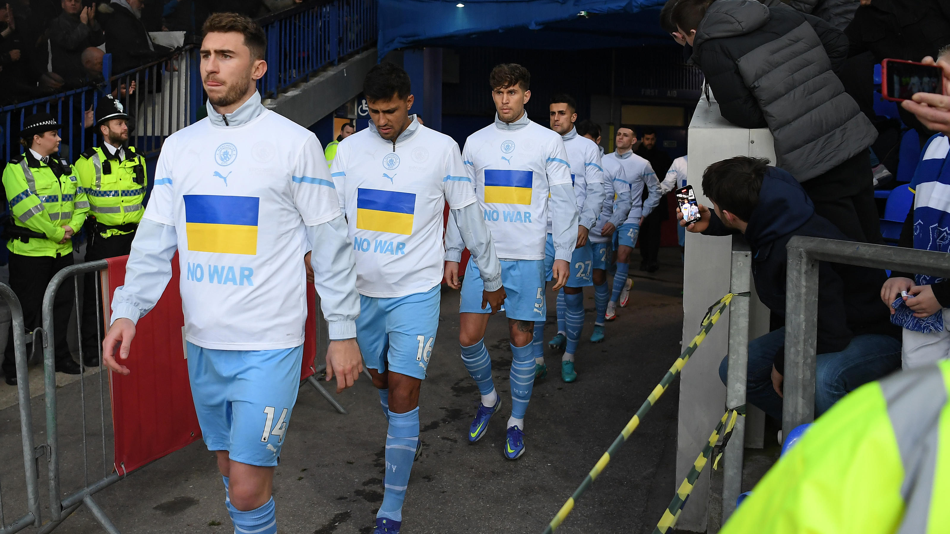 LIVERPOOL, ENGLAND - FEBRUARY 26: Aymeric Laporte of Manchester City leads their team out with Ukrainian flags on their jackets to indicate peace and sympathy with Ukraine prior to the Premier League match between Everton and Manchester City at Goodi