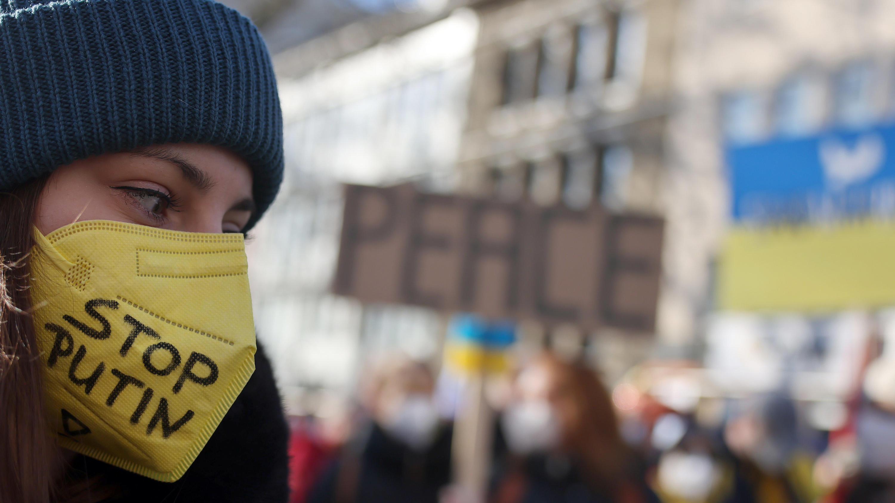 28.02.2022, Nordrhein-Westfalen, Köln: Eine Teilnehmerin der Friedensdemonstration am Rosenmontag trägt eine gelbe FFP2-Maske mit der Aufschrift "Stop Putin". Nach dem russischen Angriff auf die Ukraine wurde das Rosenmontagsfest abgesagt, stattdesse