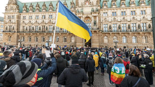 27.02.2022, Hamburg: Ein Kundgebungsteilnehmer hält eine ukrainische Fahne bei einer Demonstration auf dem Rathausmarkt gegen den russischen Angriff auf die Ukraine. Foto: Markus Scholz/dpa +++ dpa-Bildfunk +++