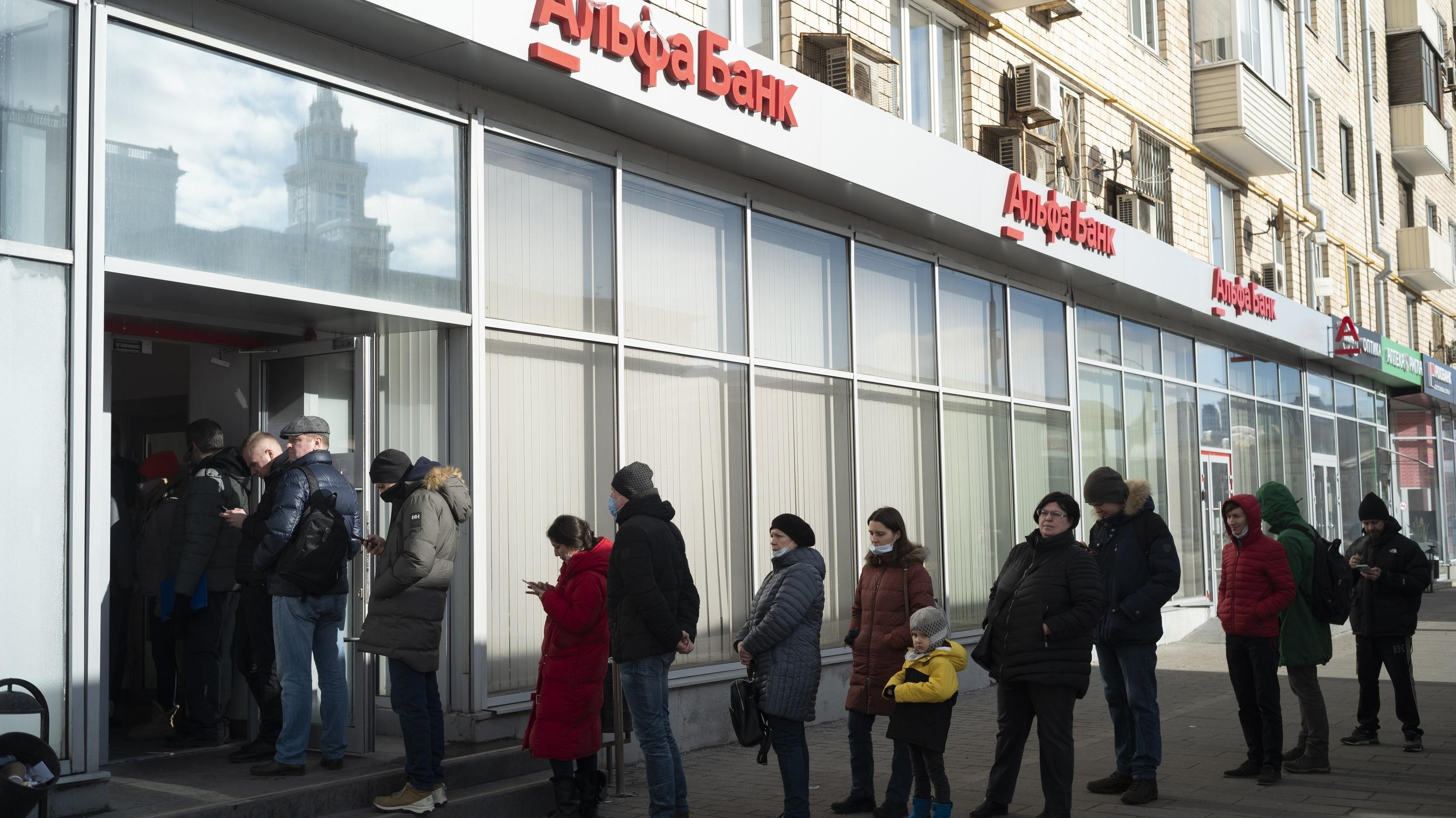 27.02.2022, Russland, Moskau: Menschen stehen in einer Schlange, um Geld von einem Geldautomaten der Alfa Bank abzuheben.  Russische Truppen haben den erwarteten Angriff auf die Ukraine gestartet. Foto: Victor Berzkin/AP/dpa +++ dpa-Bildfunk +++