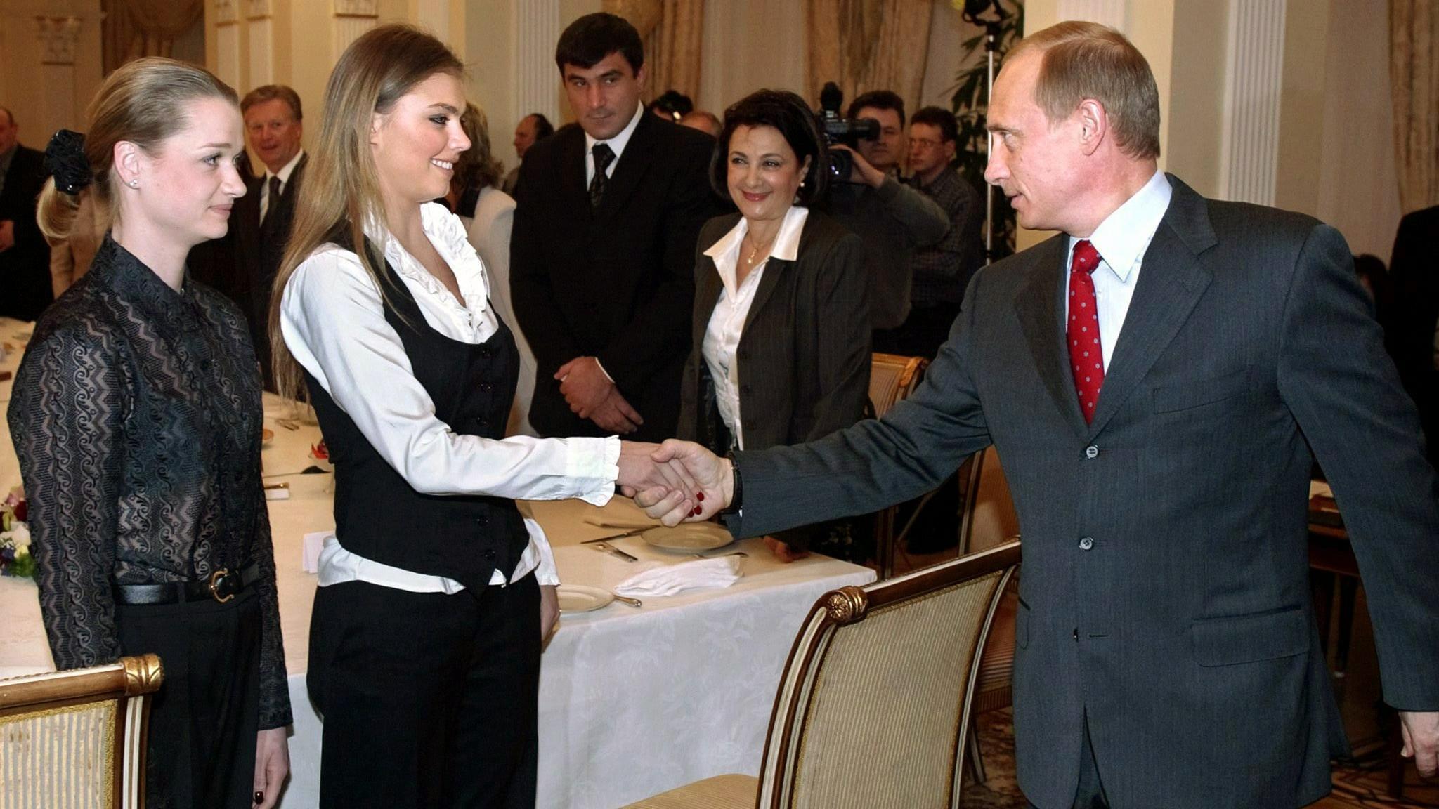 ARCHIV - Der russische Präsident Wladimir Putin begrüßt am 10.03.2004 die Sportgymnastin Alina Kabajewa (M) und die Turnerin Swetlana Chorkina während eines Treffens mit Sportlern, die an den Olympischen Spielen in Athen teilnehmen sollen. In Russlan