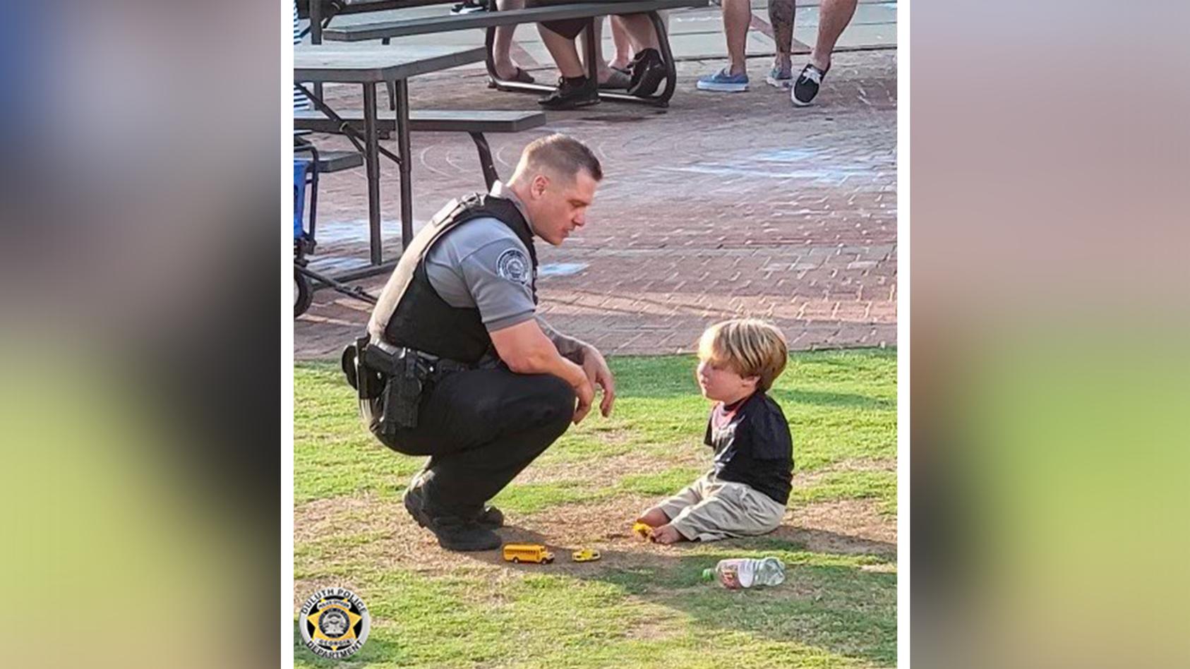 Kleiner Junge und Polizist auf Wiese während sie sich unterhalten