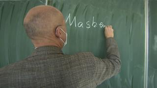 Schulleiter Gerrit Ulmke schreibt "Maske" an eine Tafel am Helmholtz-Gymnasium in Frankfurt.
