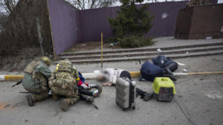 Ukrainian servicemen try to help people wounded, in the town of Irpin, Ukraine, Sunday, March 6, 2022. With the Kremlin's rhetoric growing fiercer and a reprieve from fighting dissolving, Russian troops continued to shell encircled cities and the number of Ukrainians forced from their country grew to over 1.4 million. (AP Photo/Andriy Dubchak)