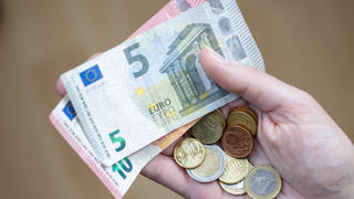 ACHTUNG: SPERRFRIST 6. JANUAR 05:00 UHR.  - ARCHIV - 09.04.2021, Bayern, Nürnberg: Eine Frau hält Geldscheine und Münzen in der Hand. Fast ein Fünftel aller Vollzeitbeschäftigten in Deutschland sind Geringverdiener. Sie müssen mit einem Bruttoarbeitsentgelt unter 2284 Euro im Monat über die Runden kommen. Das geht aus einer Studie des Wirtschafts- und Sozialwissenschaftlichen Instituts (WSI) der gewerkschaftsnahen Hans-Böckler-Stiftung hervor. (zu dpa "Fast jeder dritte Vollzeitbeschäftigte in Brandenburg Geringverdiener") Foto: Daniel Karmann/dpa +++ dpa-Bildfunk +++