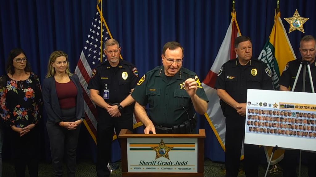 Foto einer Pressekonferenz: Am Rednerpult steht Grady Judd, Sheriff von Prost, der die Ergebnisse einer Operation gegen Prostitution vorstellt