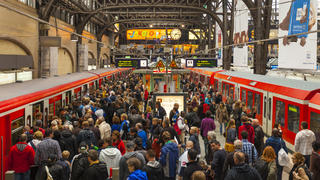 Viele Menschen an Bahnhof steigen in Züge ein