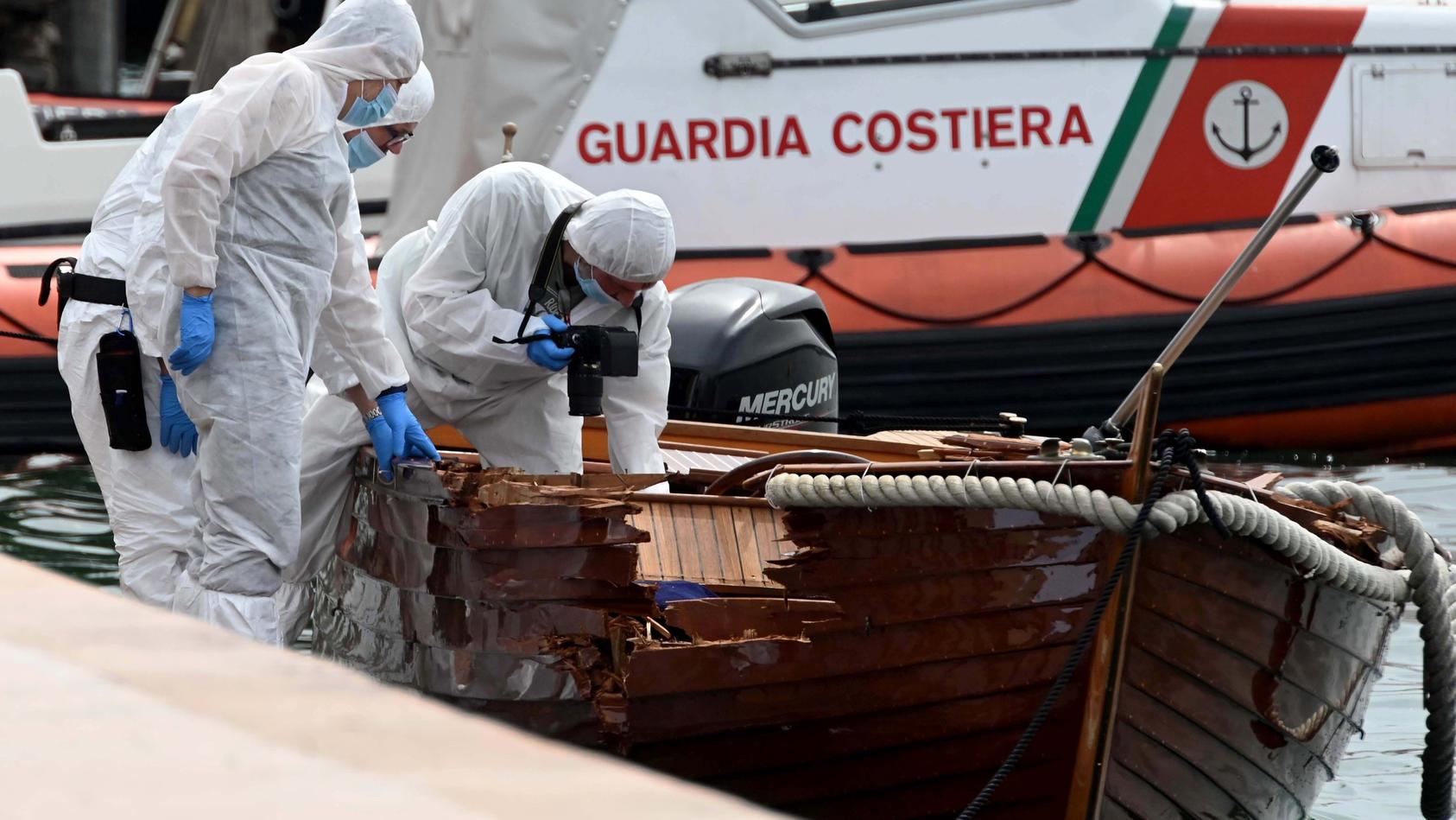 ARCHIV - 20.06.2021, Italien, Salo: Forensiker begutachten den Schaden an einem Boot im Hafen von Salo. Zwei Münchner sollen in einer Nacht im Juni ein Motorboot gesteuert haben, das mit einem kleinen Boot kollidierte. Dabei starben die beiden Insass