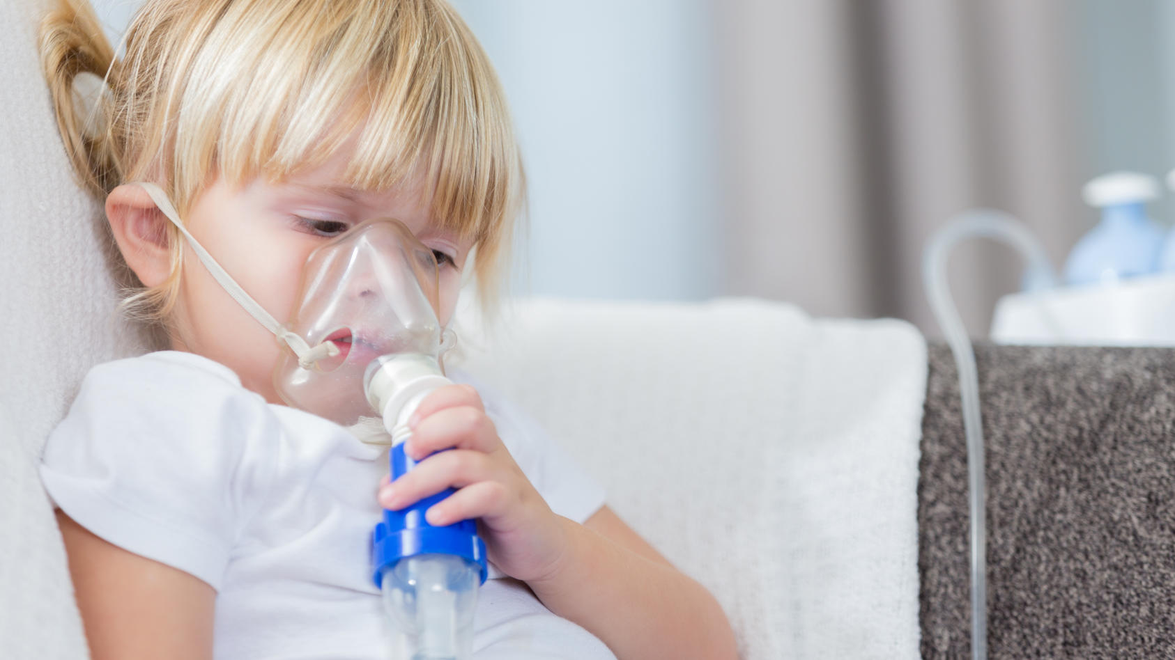Ein kleines Mädchen ist an Mukoviszidose erkrankt und nutzt ein Beatungsgerät, um besser atmen zu können.