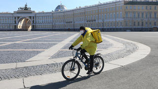 Fahrer von Yandex Foods auf Fahrrad auf dem leeren Palace Square in St. Petersburg