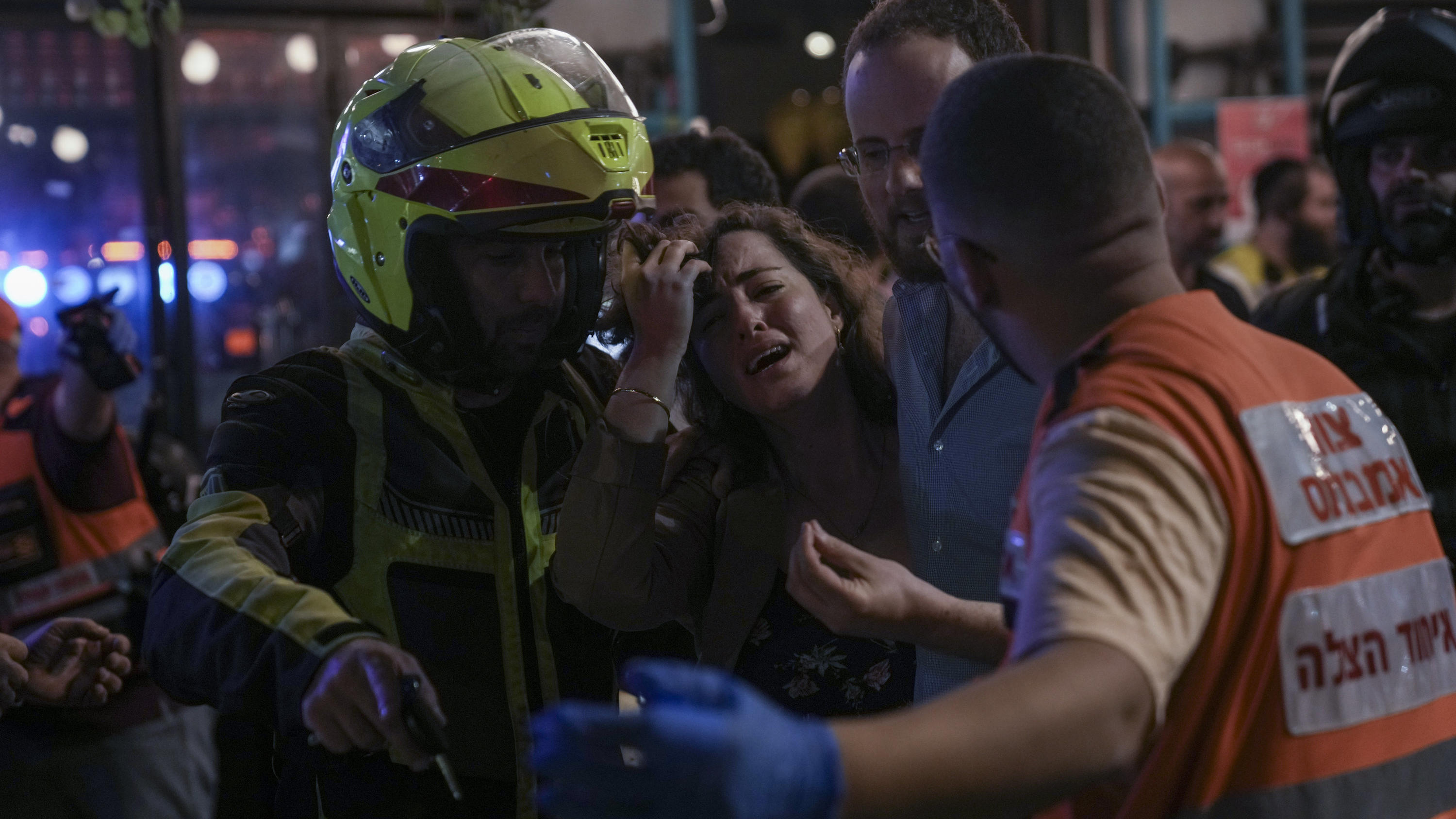 A woman reacts at the scene of a shooting attack In Tel Aviv, Israel, Thursday, April 7, 2022. Israeli police say several people were wounded in a shooting in central Tel Aviv. The shooting on Thursday evening occurred in a crowded area with several 