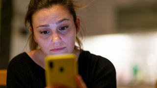 Besorgte Frau schaut auf ihr Smartphone