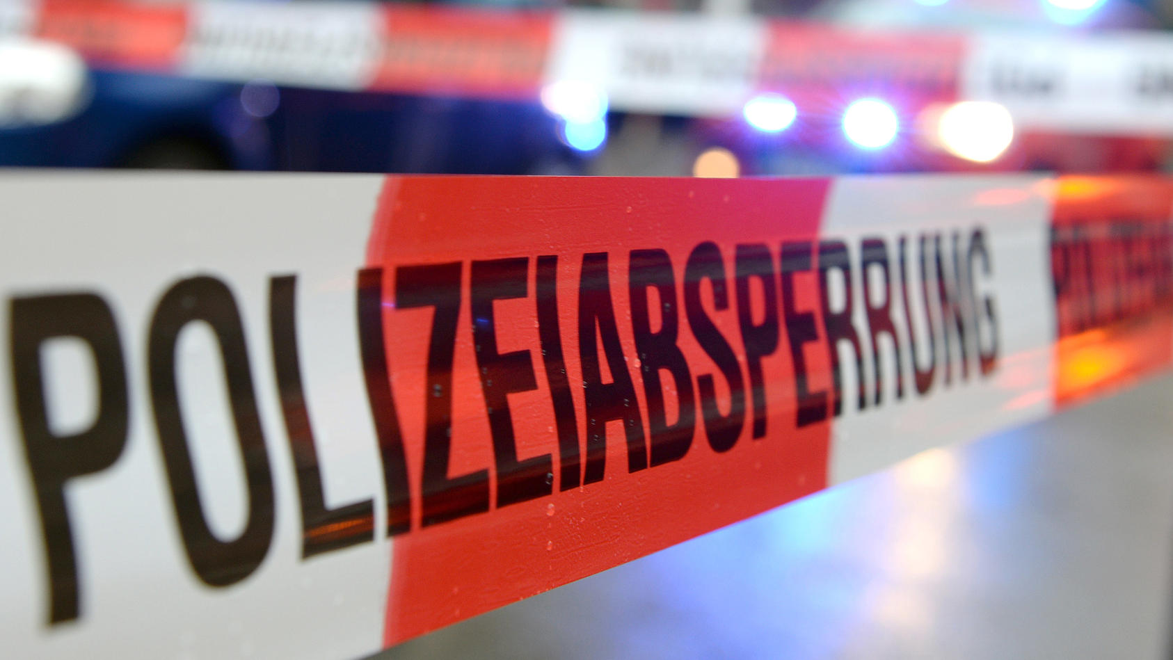 ARCHIV - ILLUSTRATION - Ein Flatterband mit der Aufschrift «Polizeiabsperrung» ist am 05.11.2014 in Freiburg (Baden-Württemberg) an einem Einsatzort vor einem Feuerwehrfahrzeug mit Blaulicht zu sehen. Foto: Patrick Seeger/dpa (zu dpa «Mehr Sicherheit