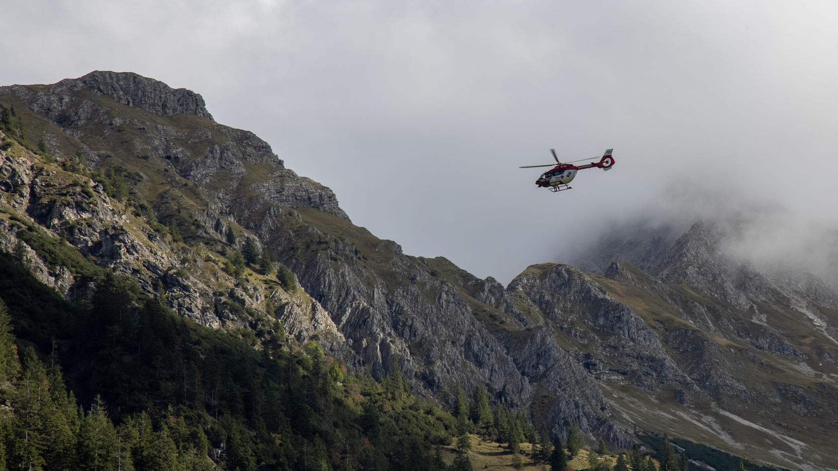 Der Rettungshubschrauber RK2 ist in den Alpen bei Oberstdorf bei einem Bergunfall mit der Rettungswinde im Einsatz.