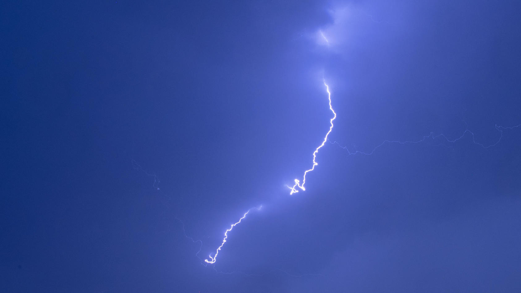 31.07.2019, Mecklenburg-Vorpommern, Pokrent: Ein Blitz ist bei einem starken Gewitter über einer Windkraftanlage zu sehen. Der Deutsche Wetterdienst hatte für Mecklenburg-Vorpommern vor örtlich starken Gewittern, teils mit Starkregen mit rund 20 Lite