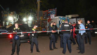 01.05.2022, Berlin: Polizeibeamte stehen auf dem Gelände eines Rummels am Columbiadamm.Bei einer Auseinandersetzung auf einem Berliner Rummel ist eine Person schwer verletzt worden. Im Veranstaltungsbereich der Neuköllner Maientage auf dem Columbiadamm sei es am späten Samstagabend zu der Auseinandersetzung zwischen mehreren Personen gekommen, sagte eine Polizeisprecherin. Ein dpa-Reporter berichtete, dass Schüsse gefallen seien. Der Schwerverletzte wurde in ein Krankenhaus gebracht. Foto: Paul Zinken/dpa +++ dpa-Bildfunk +++