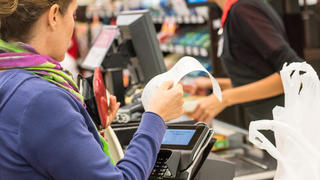 Frau zahlt an Kasse im Supermarkt