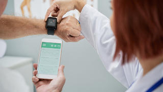 Ärztin schaut sich Smartwatch an.