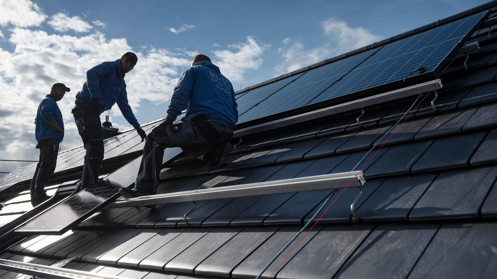 Baden-Württemberg, Stuttgart: Mitarbeiter der Firma Sontec GmbH montieren Photovoltaikmodule auf dem Dach eines Wohnhauses