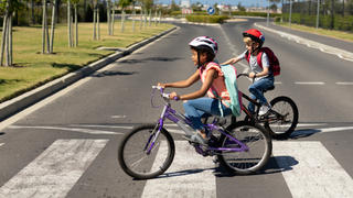Zwei Mädchen überqueren auf ihren Fahrrädern einen Zebrastreifen