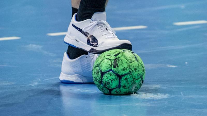 Ein Spieler hält einen Handball mit dem Fuß fest. Foto: Andreas Gora/dpa/Symbolbild