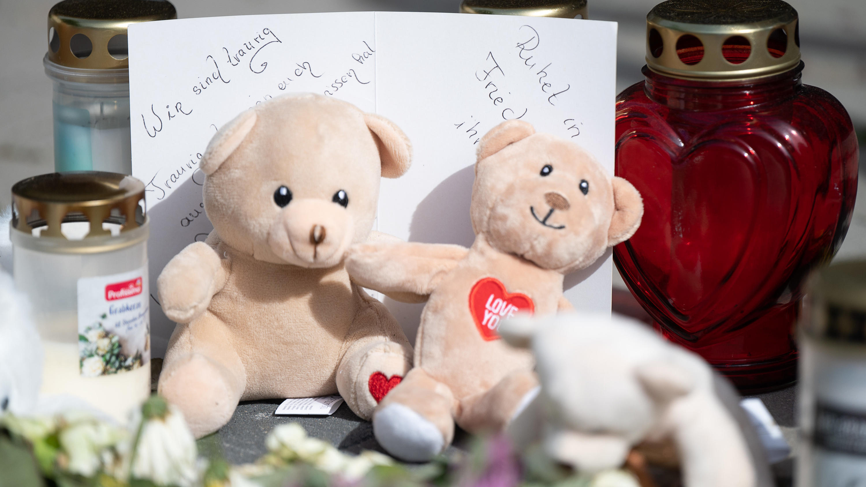 15.05.2022, Hessen, Hanau: Eine Karte mit der Aufschrift "Wir sind traurig" und "Ruhet in Frieden" liegt vor dem Hochhaus, in dem am Mittwoch, den 11. Mai, zwei Kinder getötet wurden. Die Polizei hat den gesuchten tatverdächtigen Vater am 14. Mai in 