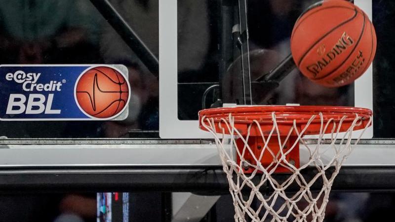 ein-ball-fliegt-auf-den-korb-zu-an-dem-ein-logo-der-basketball-bundesliga-klebt-foto-axel-heimkendpasymbolbild