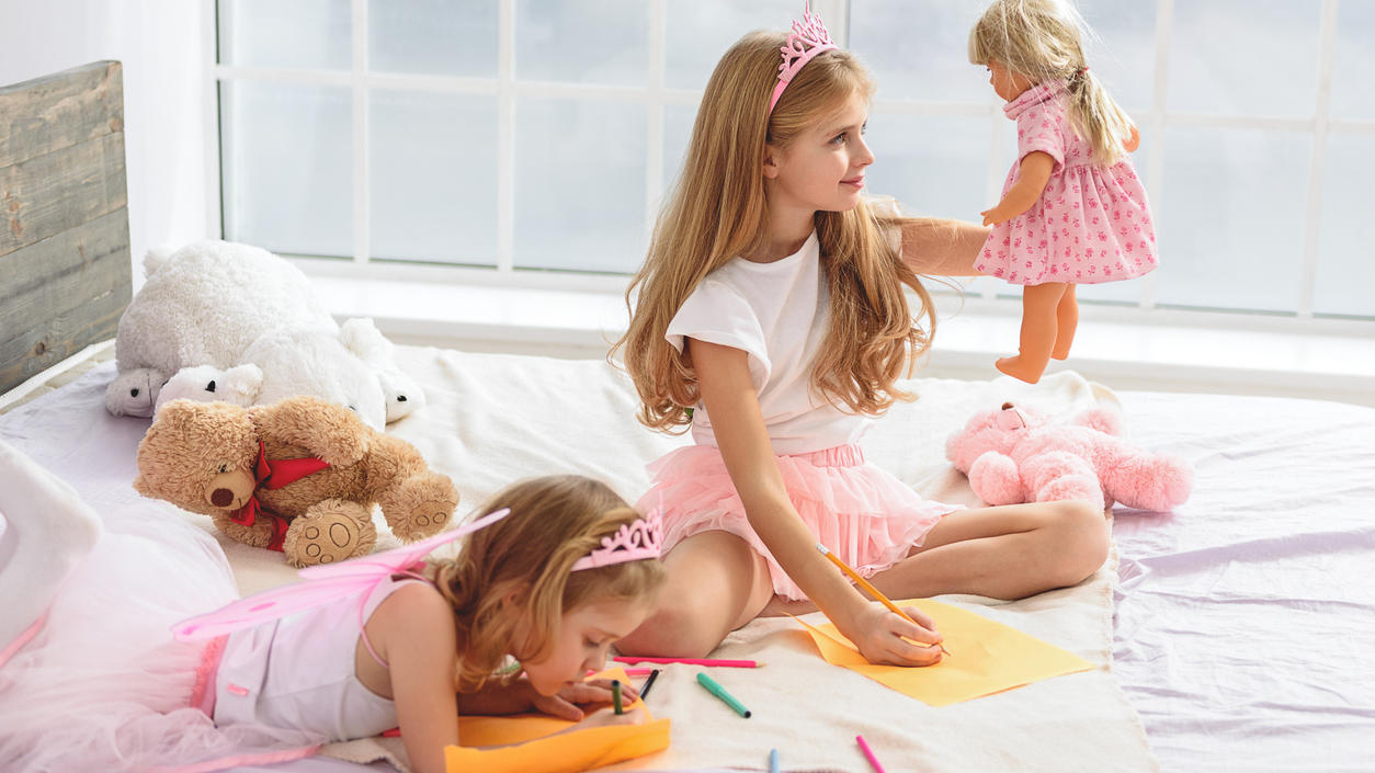 Zwei Mädchen spielen mit einem Puppenhaus - ganz in Pink