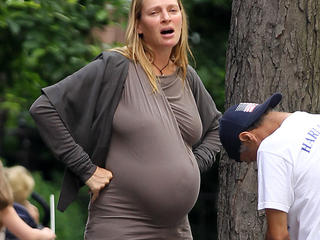 Actress Uma Thurman, wearing a brown skintight top and jeans, shows off her massive pregnant belly while buying an ice cream in New York City.