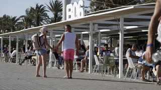 13.05.2022, Spanien, Palma: Menschen gehen am Ballermann 6 am Strand von Arenal vorbei. Der Ballermann auf Mallorca feiert sein 50-jähriges Jubiläum. Foto: Clara Margais/dpa +++ dpa-Bildfunk +++