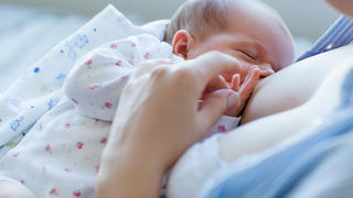 Neugeborenes saugt an Brust der Mutter