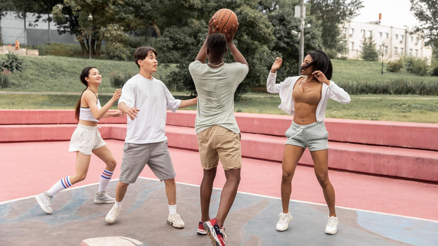 Eine Gruppe von vier Freunden spielt Basketball.