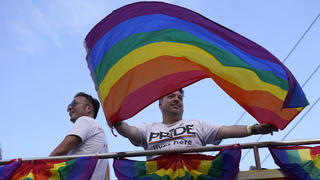 A man waves a rainbow flag in the Stonewall Pride Parade, Saturday, June 18, 2022, during Pride Month in Wilton Manors, Fla. The annual parade celebrates the historic Stonewall riots and the start of the LGBTQ human rights movement. (AP Photo/Lynne Sladky)
