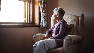 Eine Seniorin schaut aus dem Fenster.
